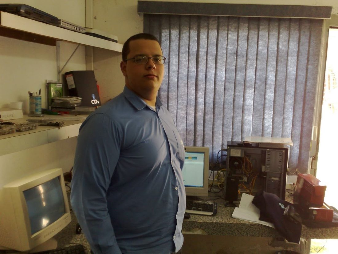 Eduardo in a computer repair room in 2008, surrounded by CRT monitors and hardware